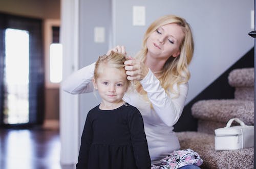 A Woman Tying Her Daughter's Hair