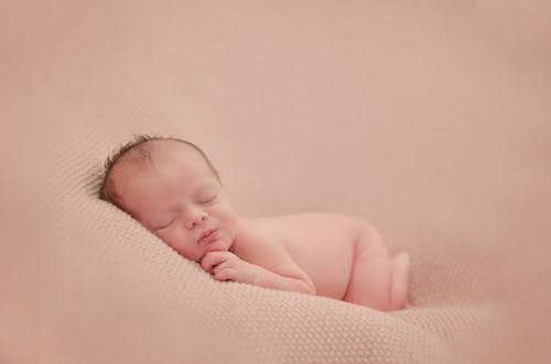 Free Baby Lying on White Textile Stock Photo