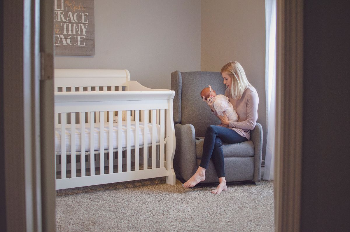 A mother holding her baby in a softly styled nursery