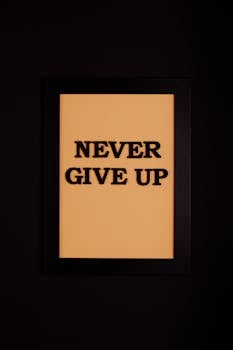 A framed motivational quote 'Never Give Up' against a black background.