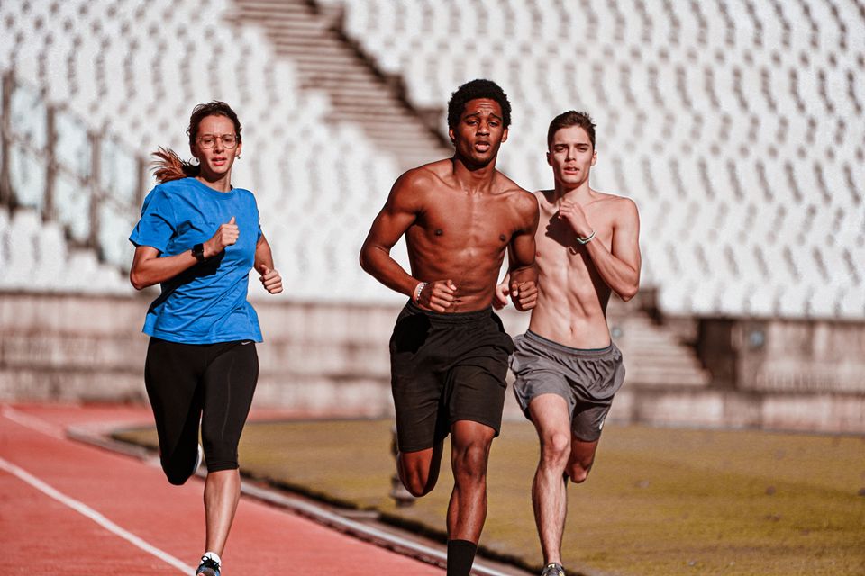 Three athletes running on an athletics track