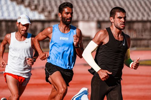 Free Three male athletes intensely focused on a track, captured mid-race showcasing their dedication. Stock Photo