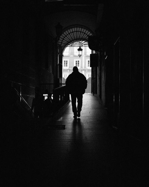 Free Silhouette of a person walking through a shadowy hallway in Madrid, Spain. Black and white tones enhance the mood. Stock Photo