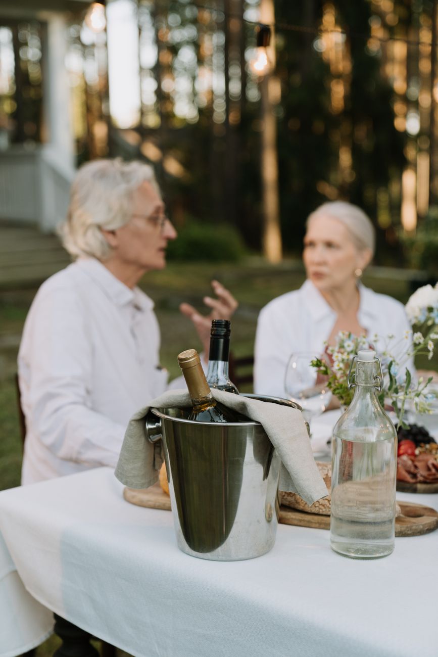 Friends sharing wine outdoors on a warm evening, the sort of setting where a lightly chilled red makes immediate sense.