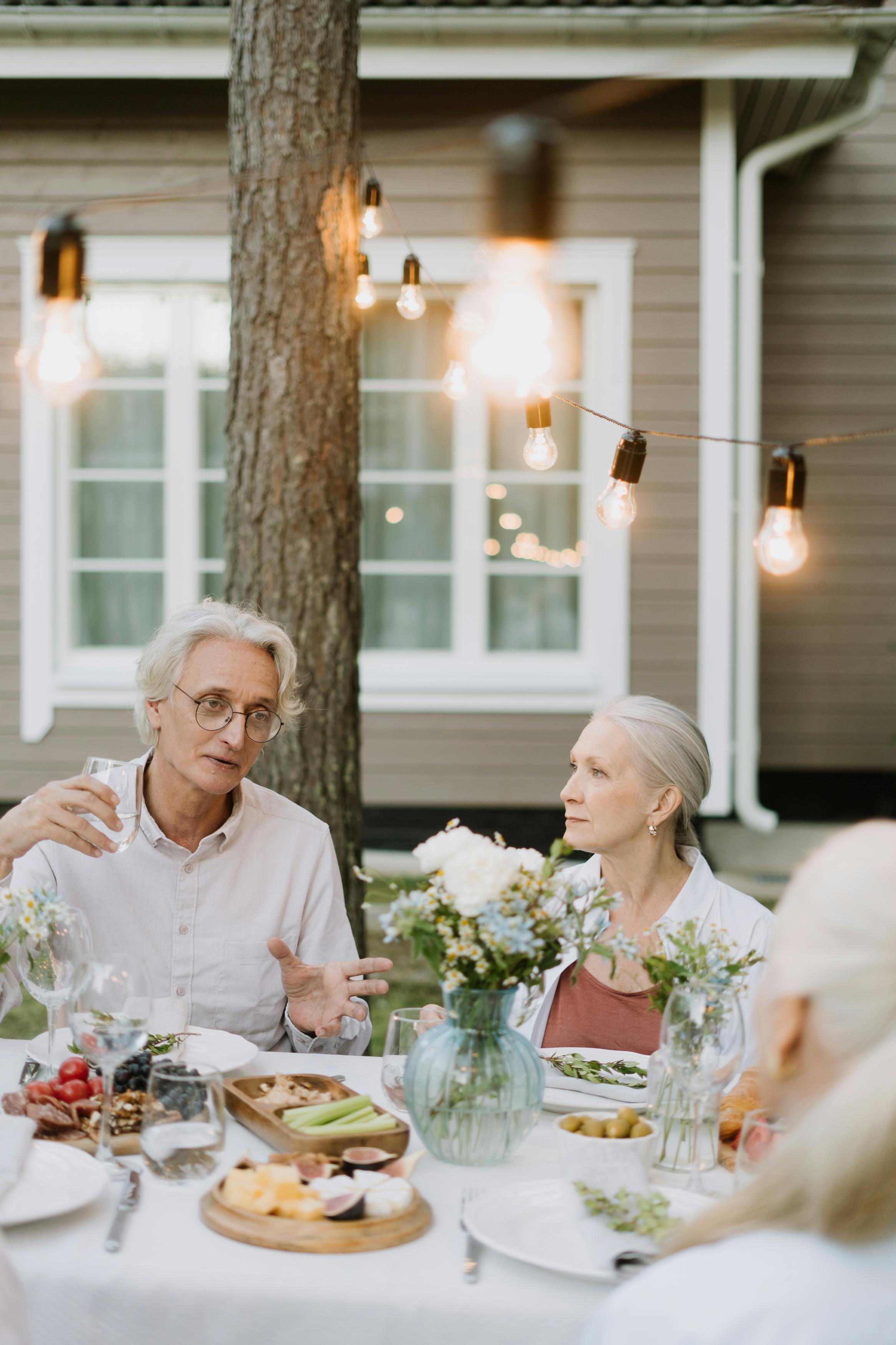 老年人在户外用餐，在一张布置精美的桌子旁交谈