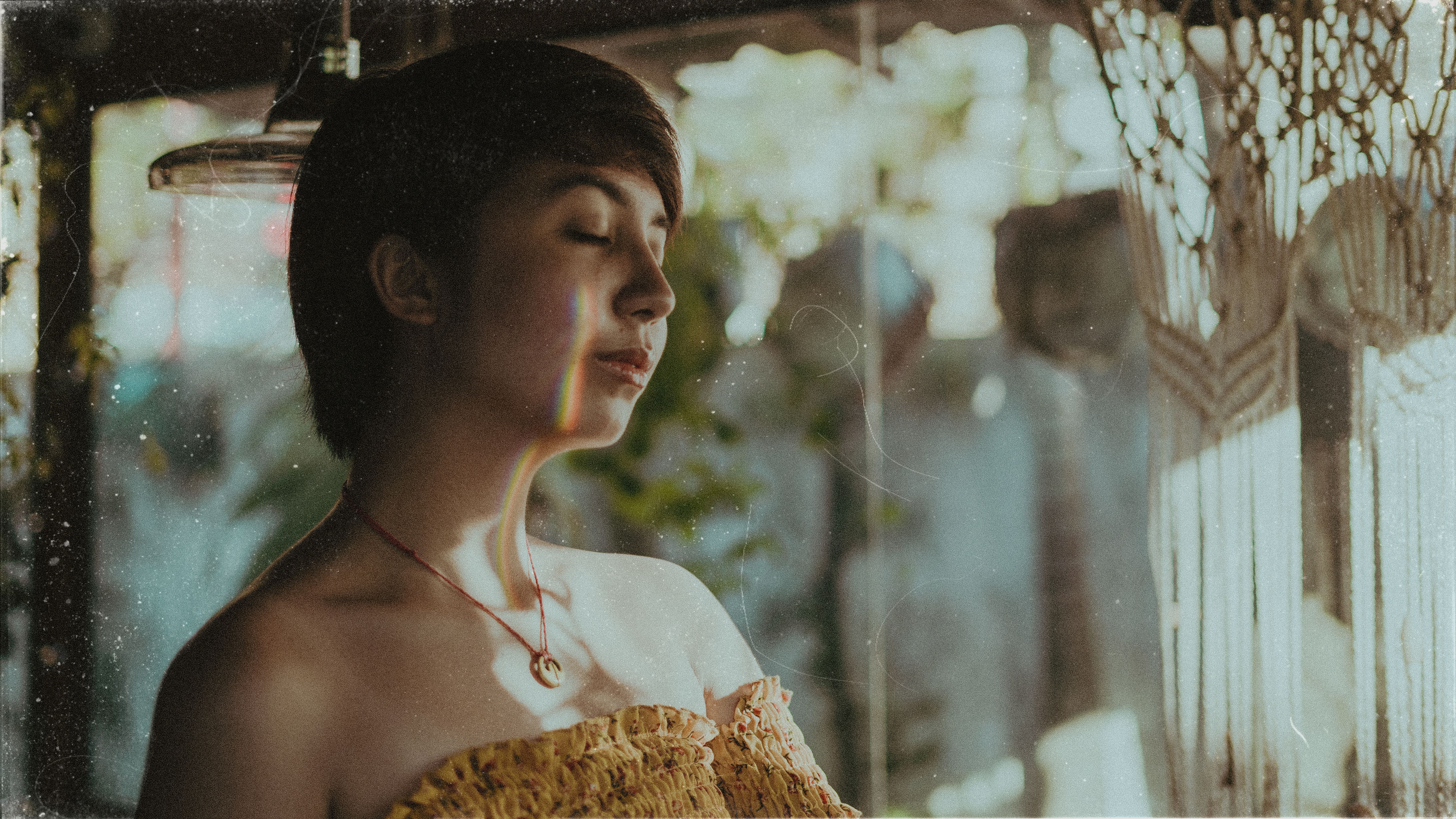 A woman enjoys a peaceful moment with closed eyes in a sunlit room, emphasizing tranquility.