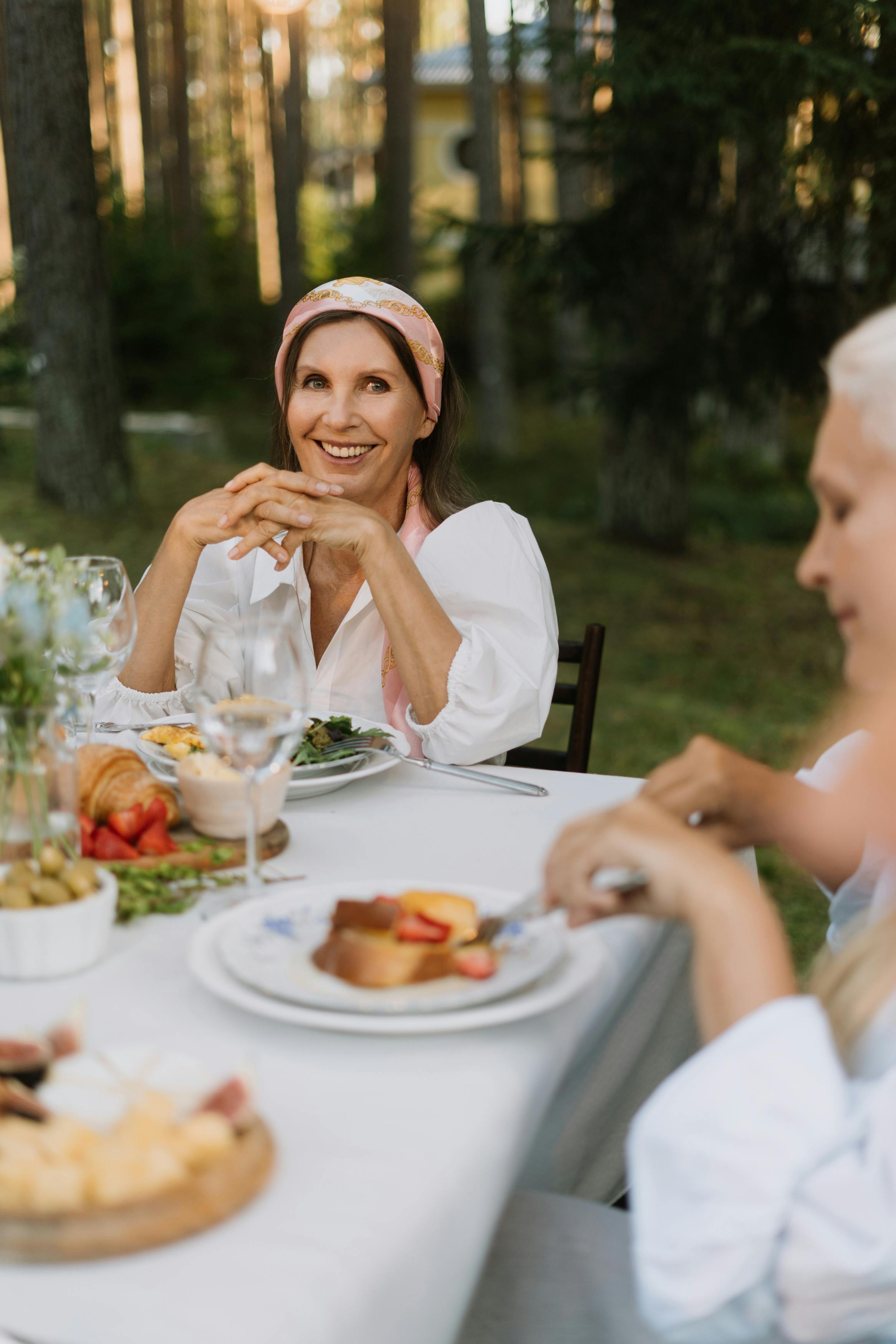 woman in white tank top sitting on chair in front of table with foods