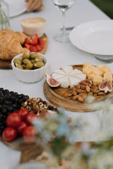 A variety of cheeses, fruits, and nuts elegantly arranged on a wooden platter, perfect for outdoor dining.