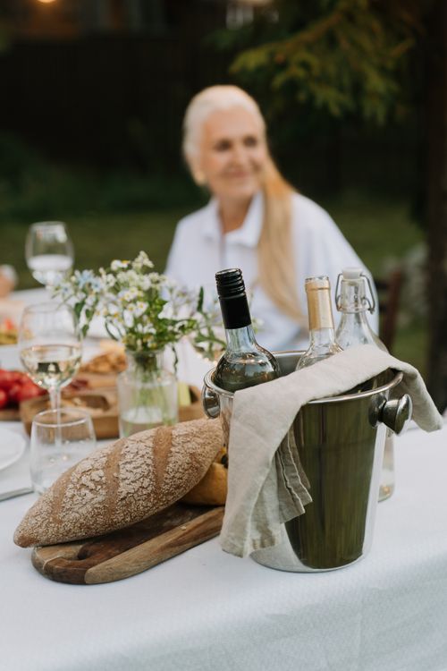 Free Outdoor dining scene with wine, bread, and floral centerpiece, suggesting a stylish gathering. Stock Photo