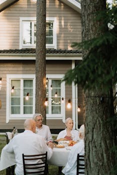Senior adults enjoy a peaceful outdoor meal at a cozy home with warm lighting and nature.
