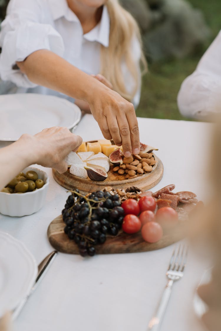 People Getting Food From A Cheese Board