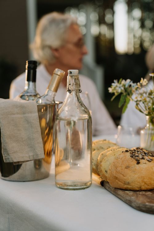 Free Cozy dinner setting outdoors with glass bottles, bread, and flowers. Stock Photo