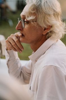 一位戴着眼镜的老人若有所思，在柔和的自然光下拍照