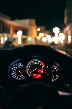 Dashboard with illuminated indicator of modern car driving along city street at night