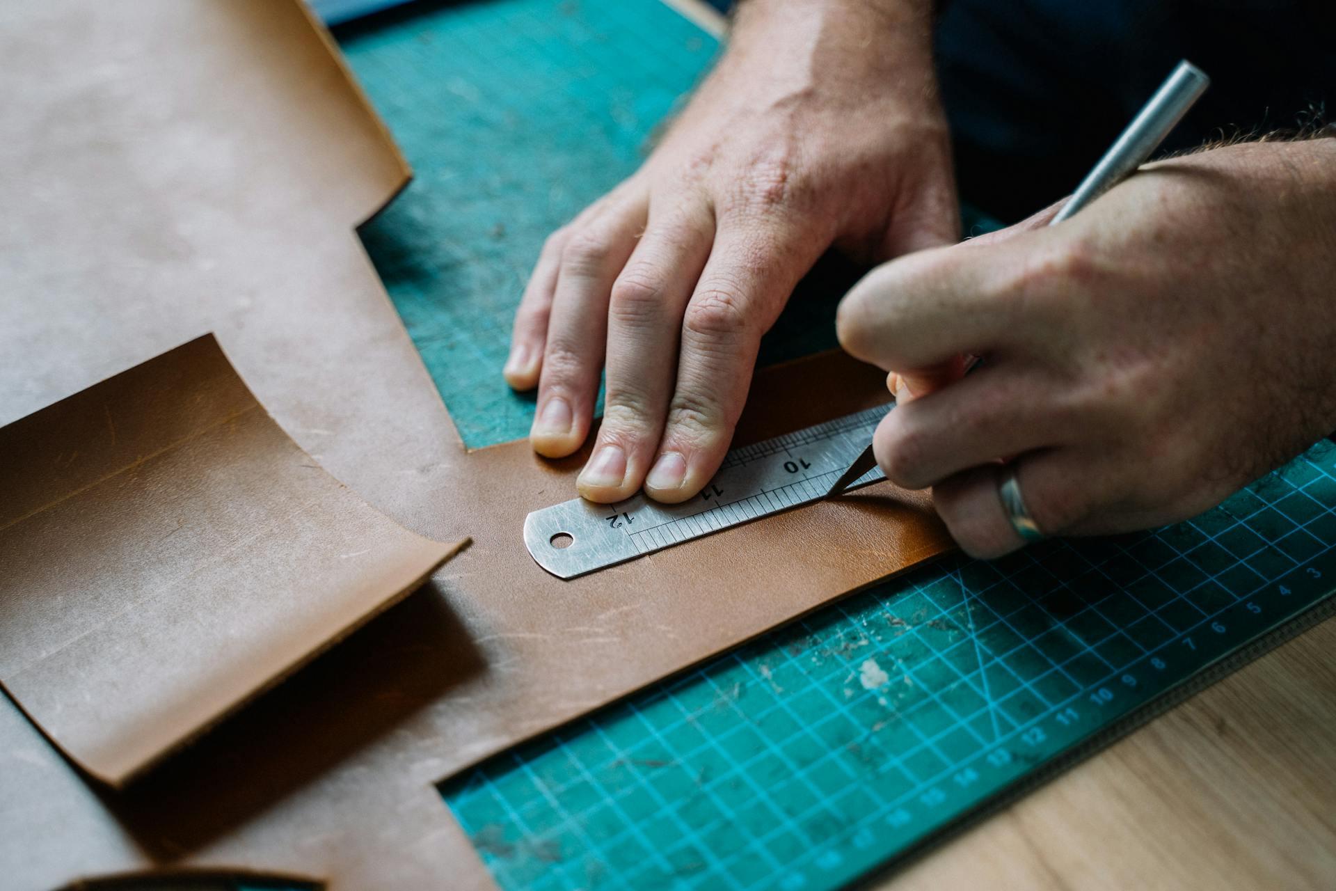 A Close-Up Shot of a Man Cutting a Leather