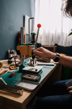 A leather artisan using specialized tools at a creative workspace indoors.