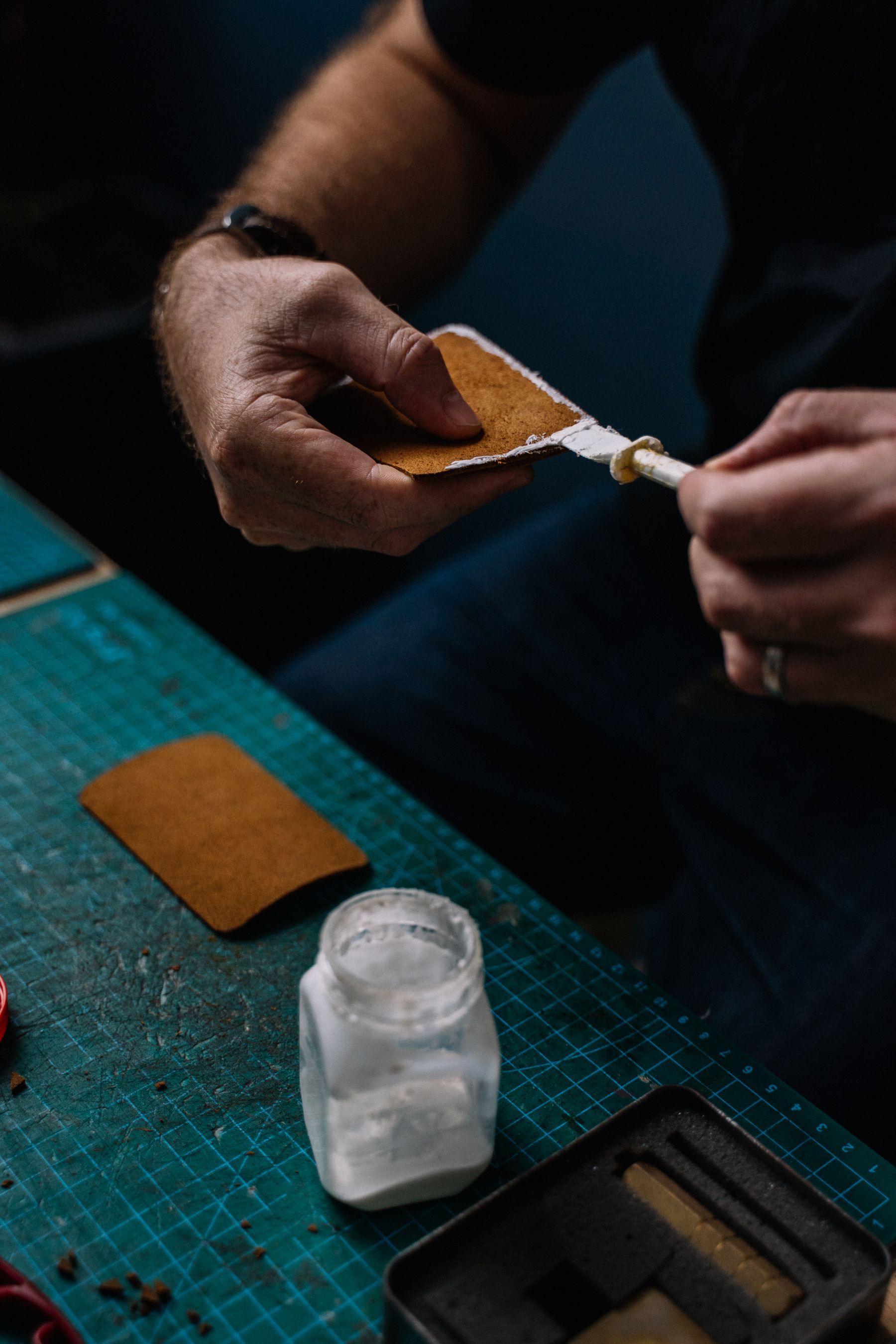 Hands working leather at a warm craft table
