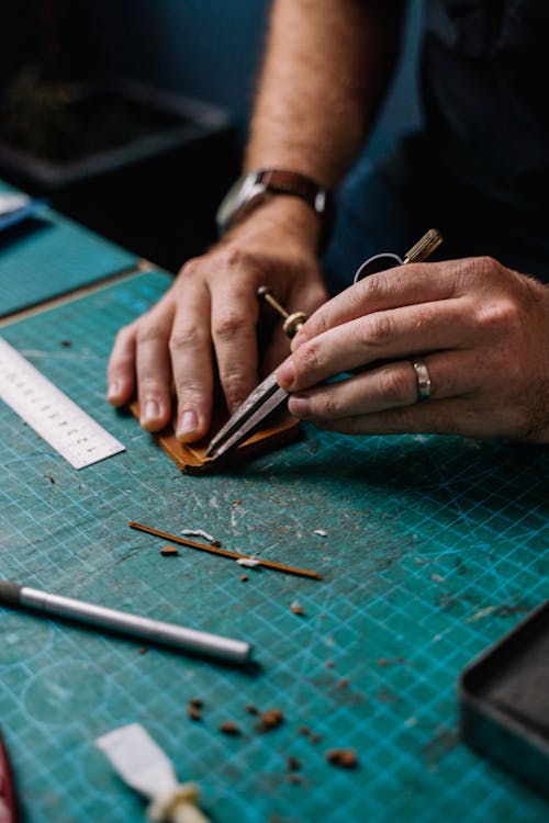 Close-up of Leathersmith Cutting a Piece of Brown Leather on a Cutting Mat