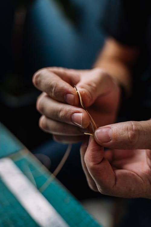 Person Holding a Thread and Needle