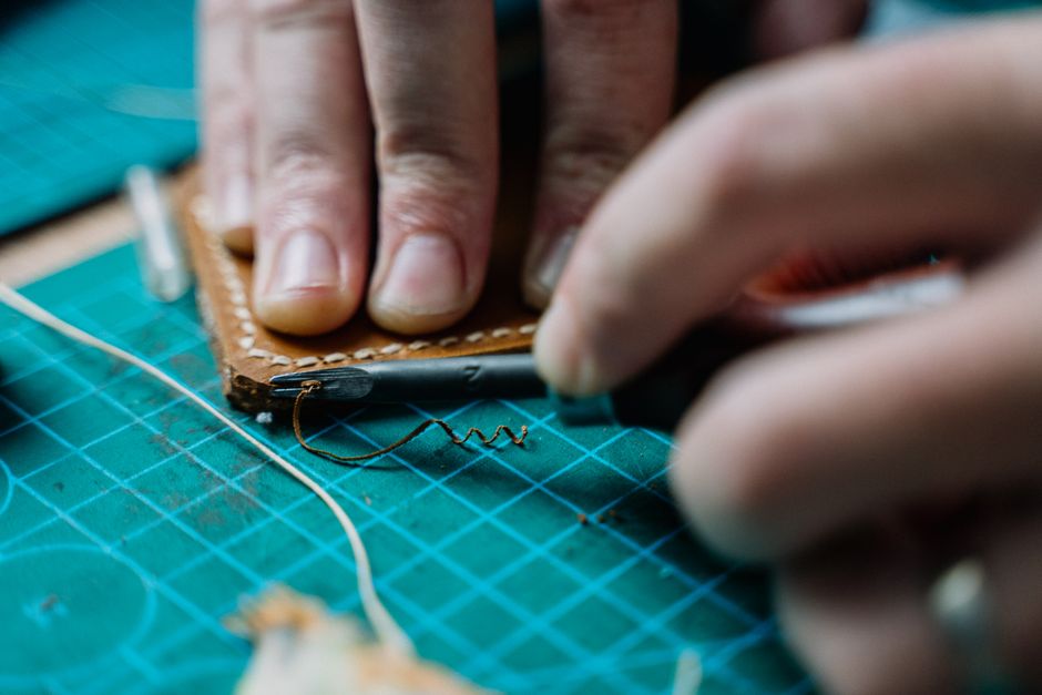 craftsman stitching a leather belt by hand craftsman stitching a leather belt by hand