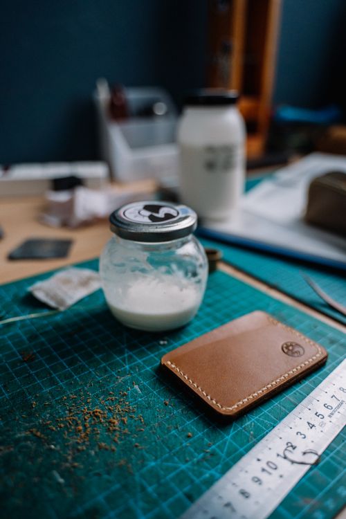 Free Close-up view of a leather crafting workspace with a leather card holder and tools. Stock Photo