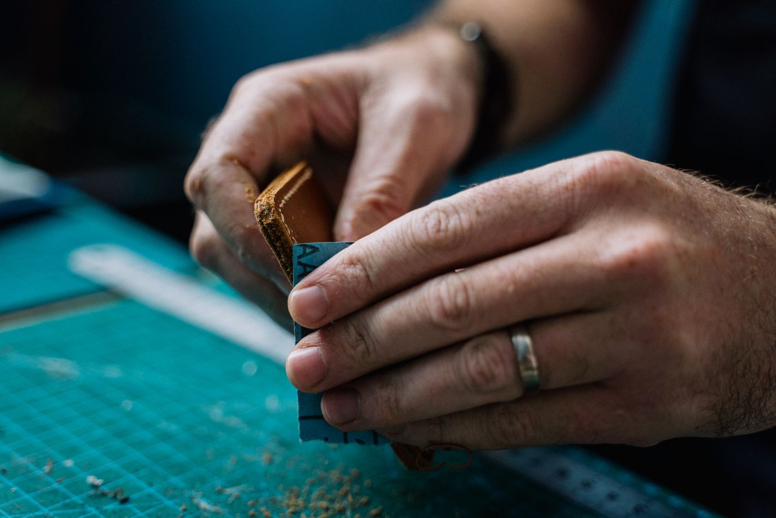 Craftsman hands sanding the edge of a handmade leather wallet