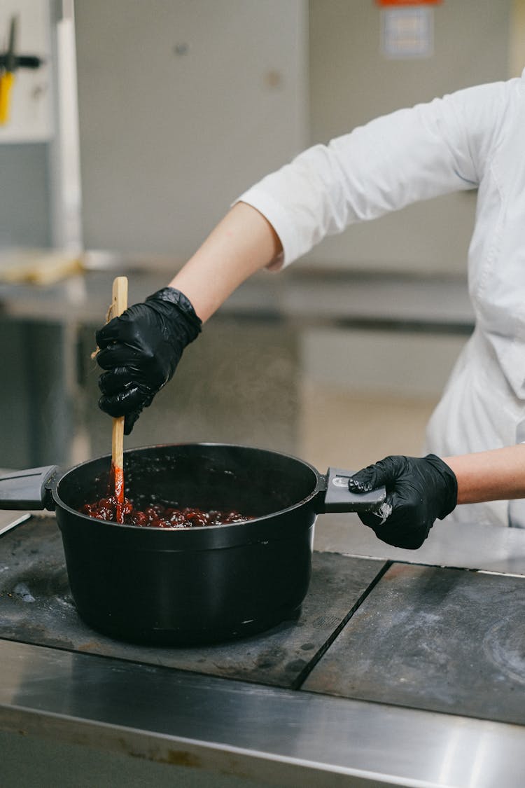 Chef In Black Gloves Cooking In A Black Pot