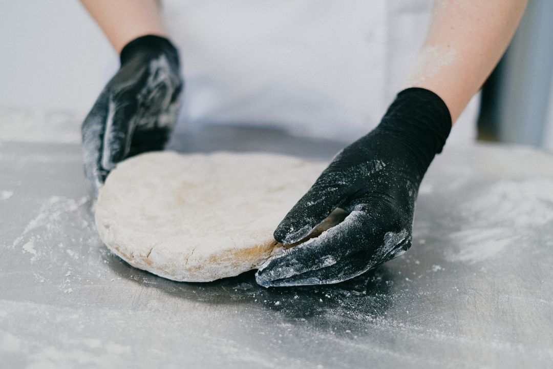 Focaccia and No-Knead Bread: The Easiest Artisan Loaves for Home Bakers 3 Hands shaping a ball of bread dough on a floured stainless steel counter