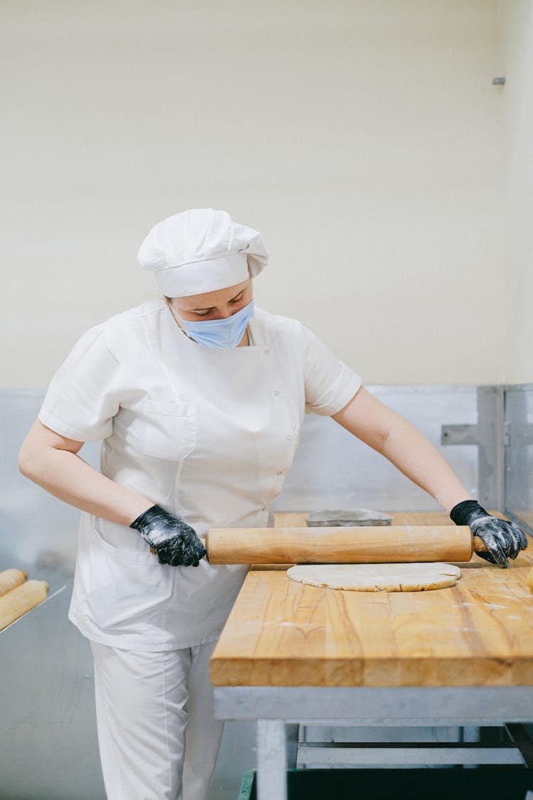 Pastry Chef Flattening A Dough