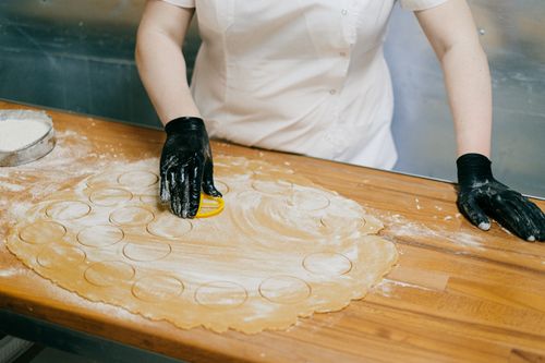 Free Chef using a cutter to prepare dough rounds for dumplings on a floured wooden table. Stock Photo
