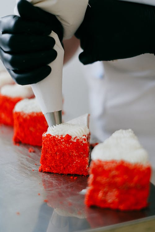 Person Putting an Icing on Top of a Cake Slice