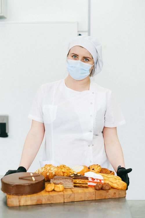 Free Pastry chef wearing face mask presenting assorted pastries on a board. Stock Photo
