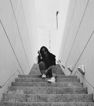 Stylish woman poses on outdoor staircase in a monochrome setting, showcasing urban fashion flair.