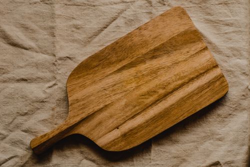 Free Rustic wooden chopping board on textured linen surface for kitchen decor Stock Photo