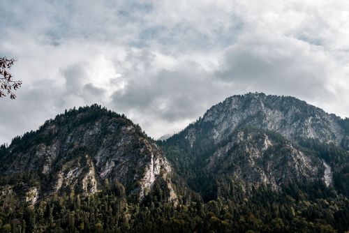 Free Majestic stony mountains covered with green trees near lush forest under cloudy sky Stock Photo