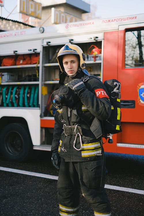 A Firefighter in Uniform Standing Near a Fire Truck