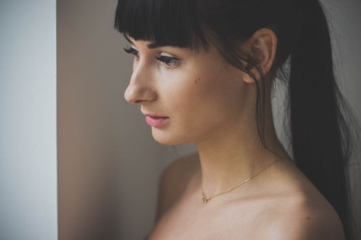 A side profile portrait capturing the elegance and beauty of a young woman indoors.