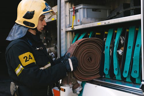 A Firefighter in Uniform Holding a Fire Host