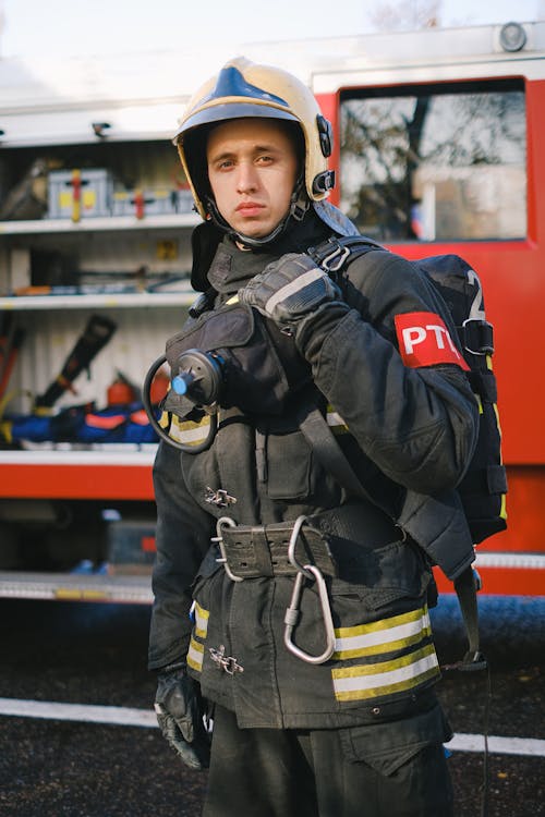 Man Wearing a Bunker Gear Standing Beside a Truck