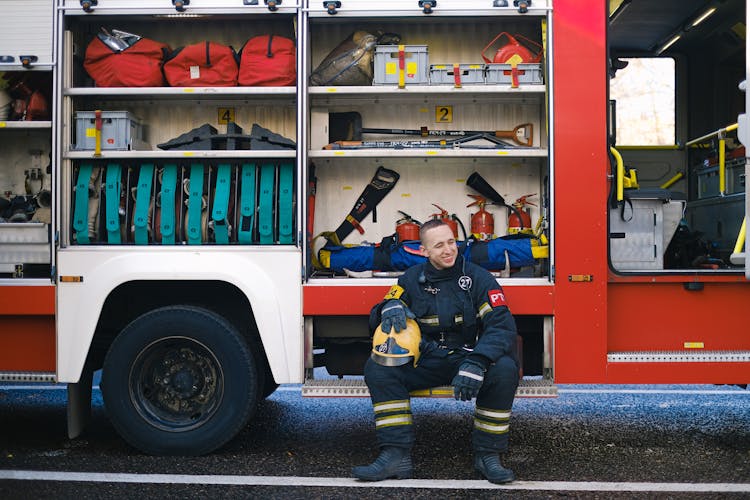 Man Smiling While Sitting On Running Board Of A Fire Truck