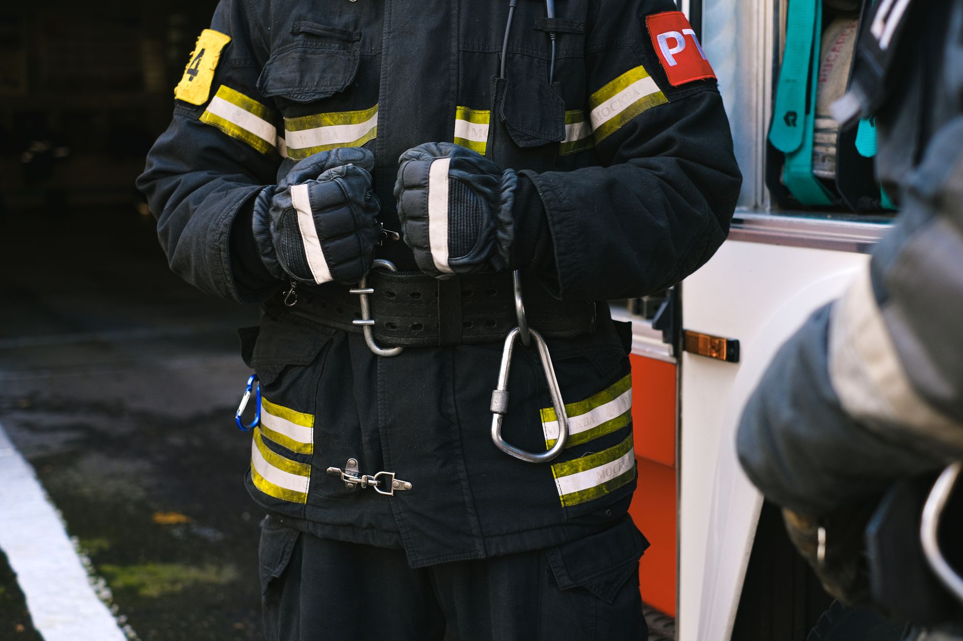 Firefighter in uniform with rescue equipment near emergency vehicle, highlighting safety and readiness.