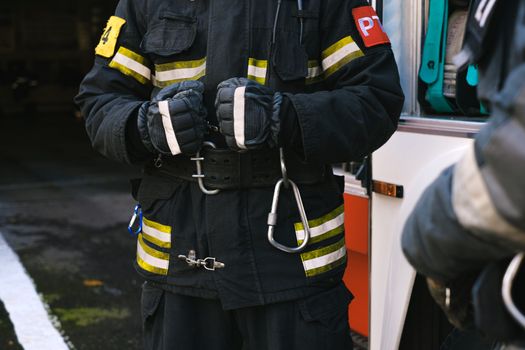 Firefighter in uniform with rescue equipment near emergency vehicle, highlighting safety and readiness.