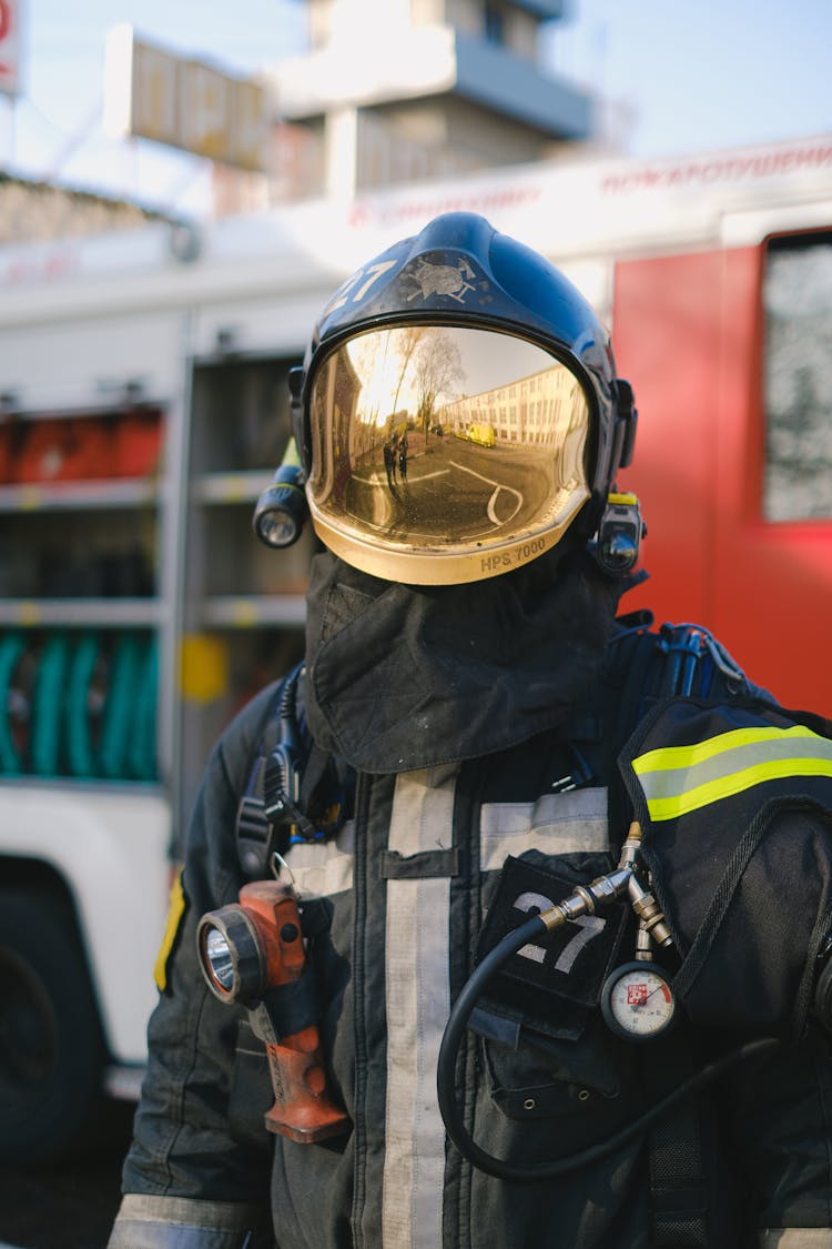 A Firefighter In Uniform Standing Near A Fire Truck