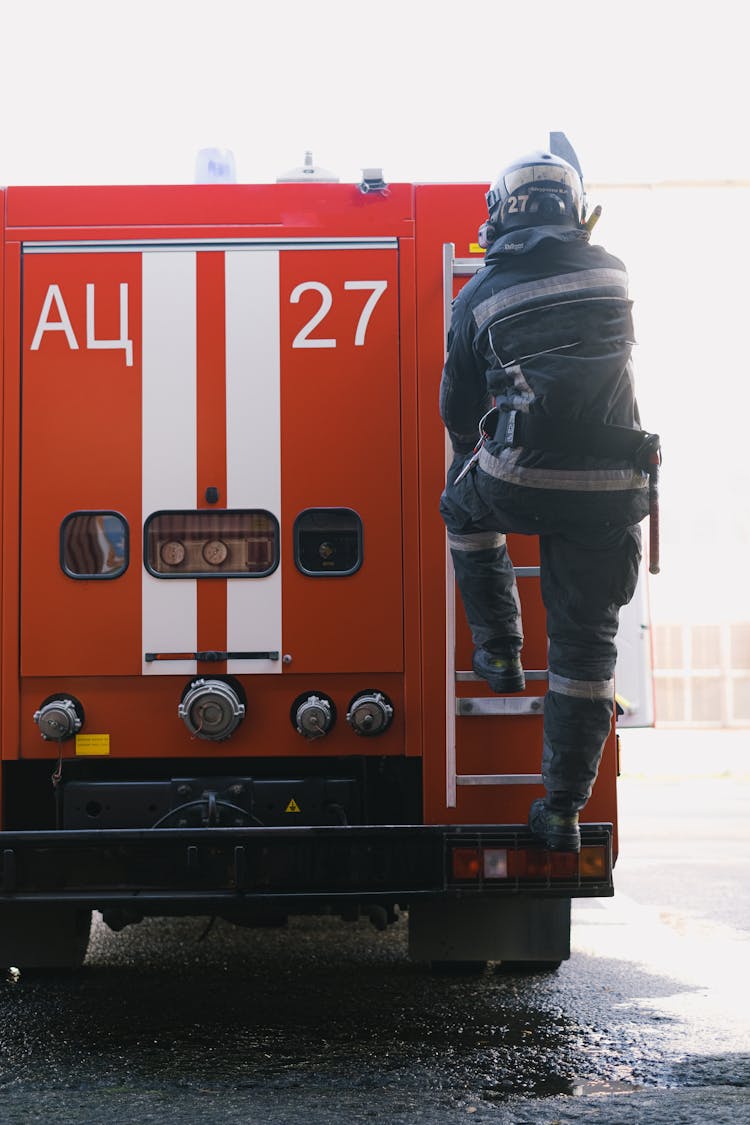 Back View Of A Fireman On Fire Truck Ladder