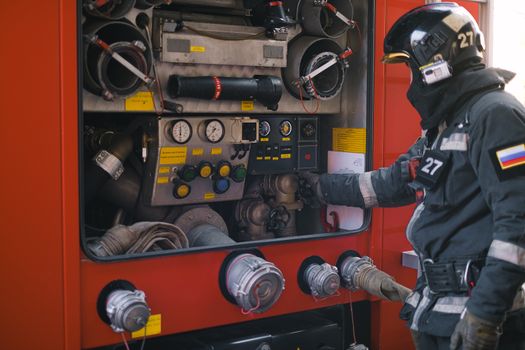 Firefighter in uniform adjusts the control panel of a fire truck. Ensuring safety and rescue operations.