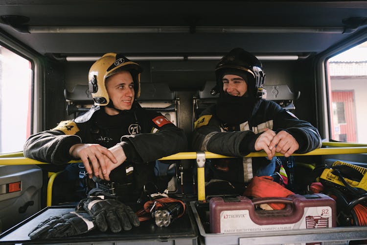 Firefighters Sitting Inside The Fire Truck And Smiling 