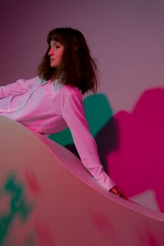 一个年轻女子若有所思地在粉红色工作室里摆姿势