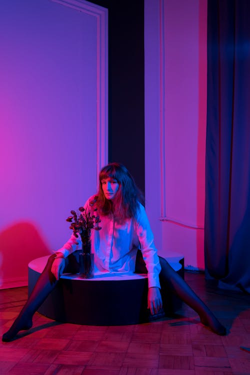 Feminine woman sitting on raised floor in dark room