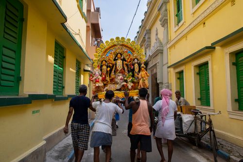 Free Men carrying a Durga statue during a festival procession in a Kolkata alley, India. Stock Photo