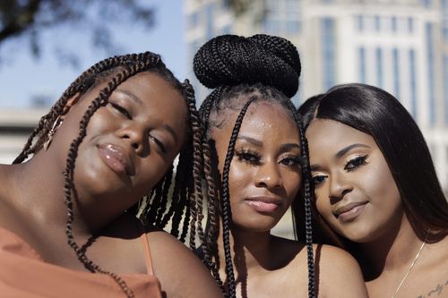 Free Three women with diverse hairstyles smile warmly while standing together outdoors. Stock Photo